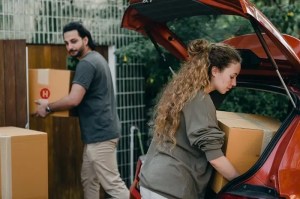 A man and a woman unpacking boxes from a car.
