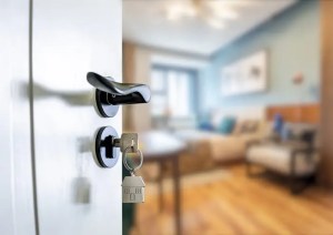 A photo of a key in an open door leading to what appears to be an apartment.
