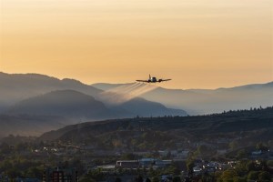 A picture of a plane flying at sunset in Kamloops spraying insecticide.