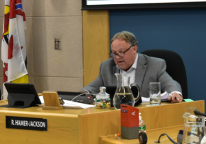 Mayor sits at head of a city council meeting.