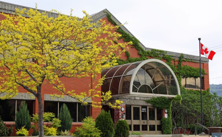 A red brick building with a Canadian flag in front.
