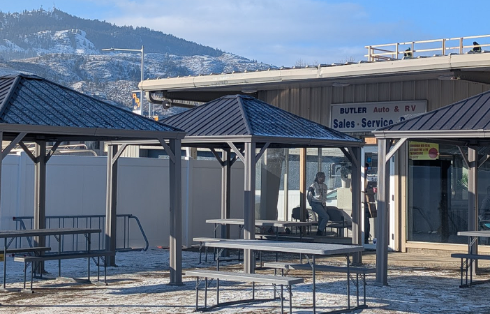 A building frontage behind gazebos and picnic tables.