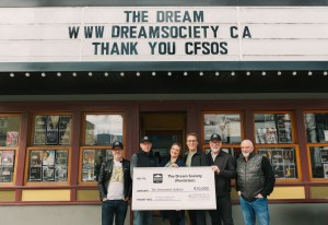 People holding a big cheque in front of the old Dream Cafe in Penticton.