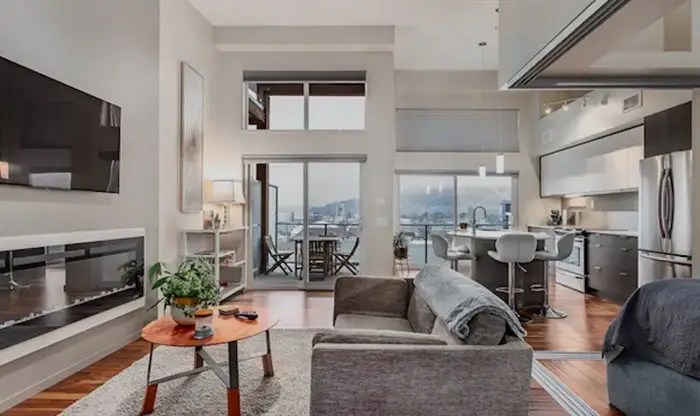 A clean, modern apartment with windows that have a view of Kelowna.