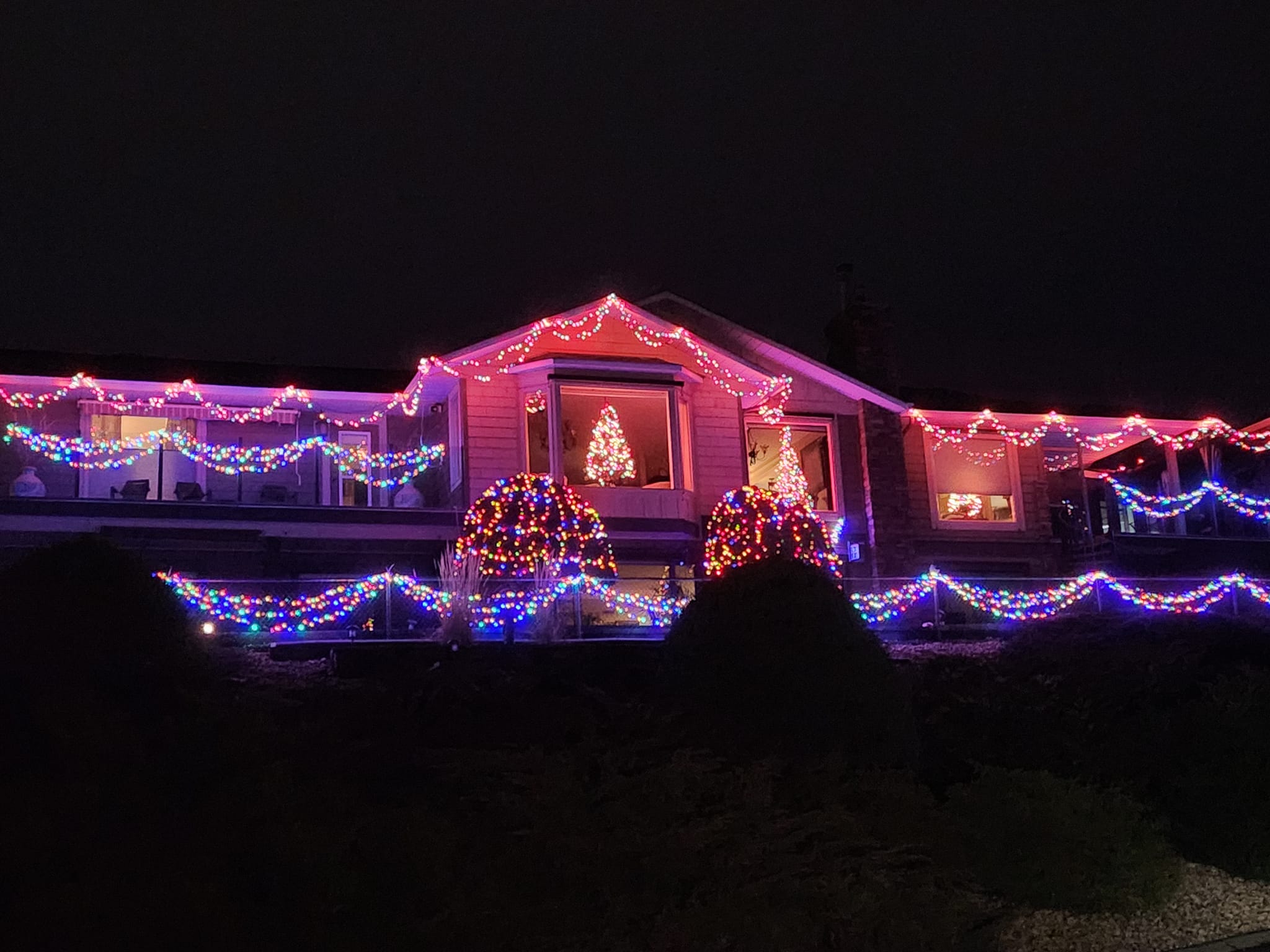 A large family home is covered with bright Christmas lights at night.