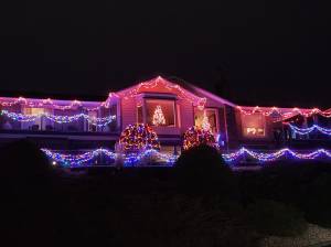 A large family home is covered with bright Christmas lights at night.