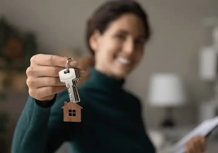 A woman smiling and holding a house key.