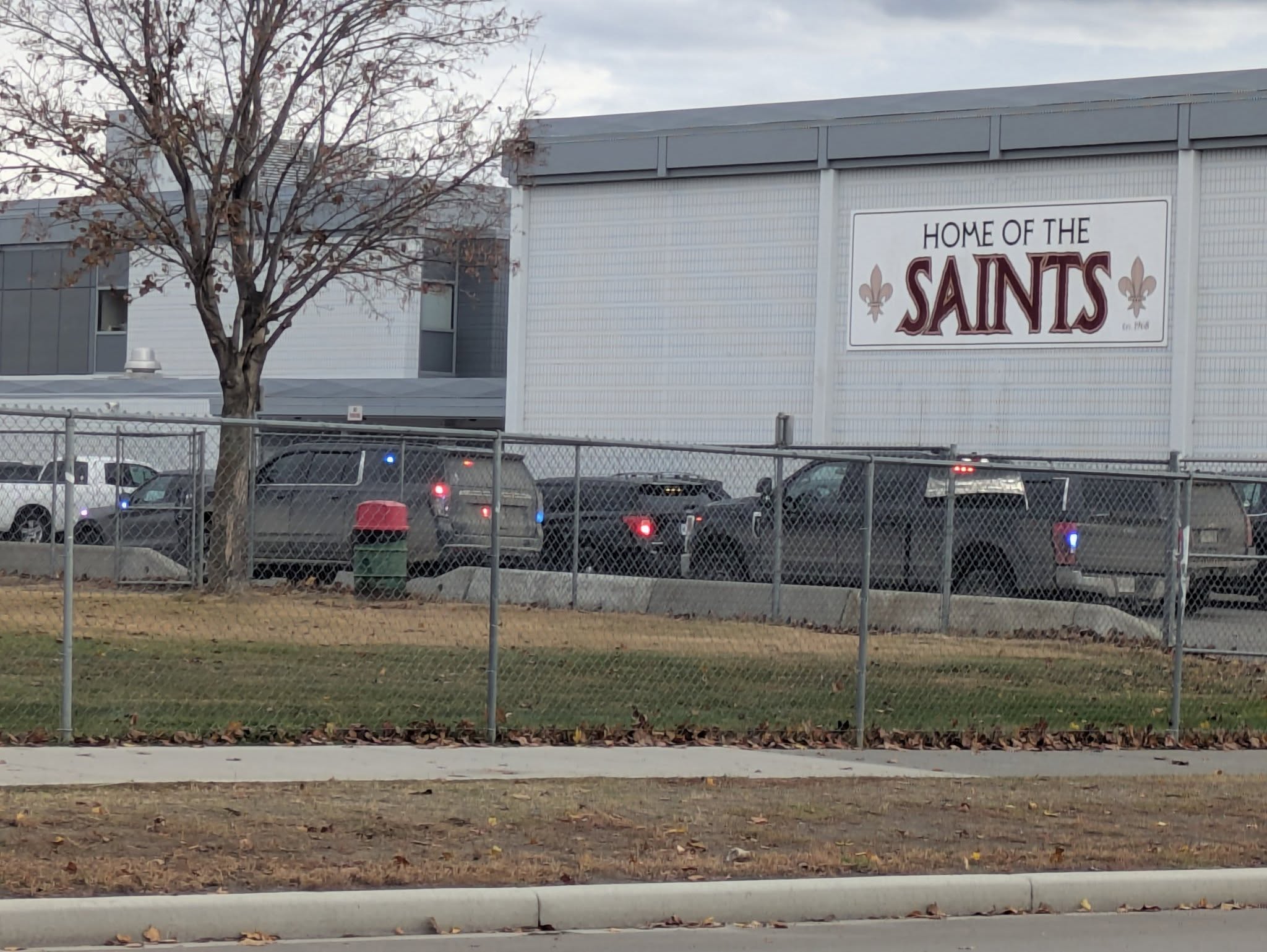 Exterior of a high school seen with multiple police vehicles in front.