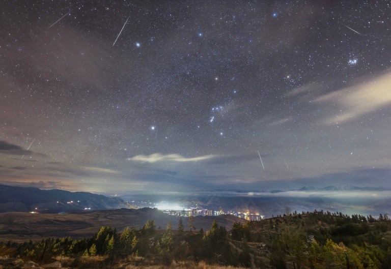 A night sky shows stars, clouds and meteors streaking across it.