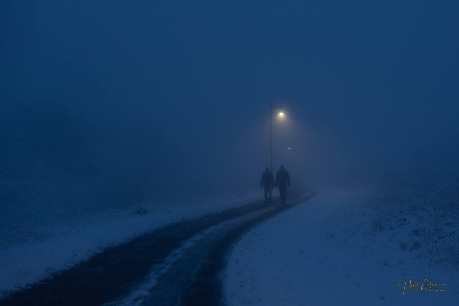 The outline of two people appear in a thick fog.