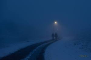 The outline of two people appear in a thick fog.