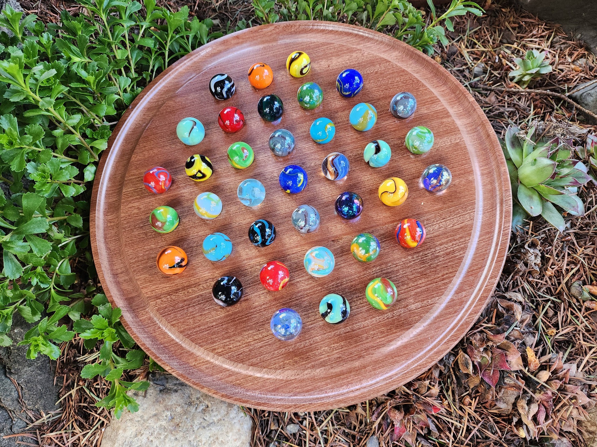 A round piece of wood has coloured marbles on it.