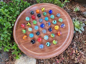 A round piece of wood has coloured marbles on it.