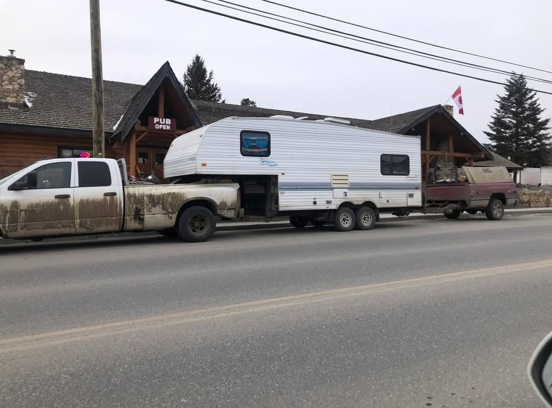 A pickup truck is connected to a trailer which is connected to a homemade trailer.