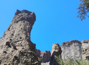 A hoodoo formation towers against a blue sky.