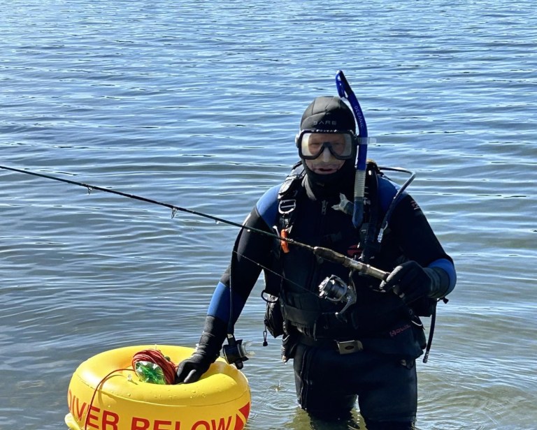 A scuba diver wads in a lake.