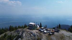 A fire tower and Jeeps are on a peak with a panoramic view.