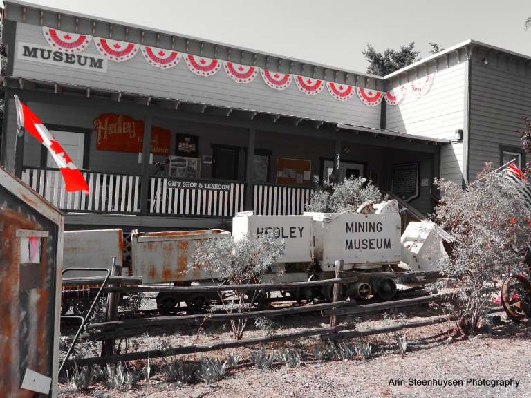A museum has a string of old mining carts in front of it.