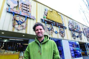 A man stands in front of a store front.