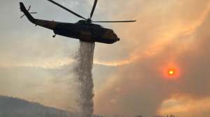 A helicopter dumps water on a wildfire.