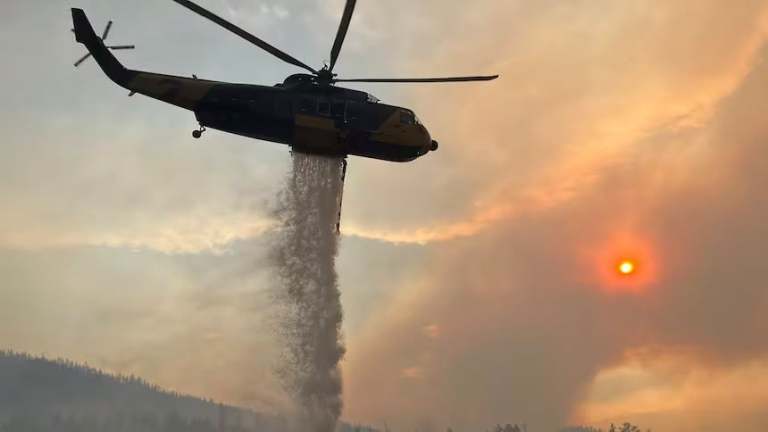 A helicopter dumps water on a wildfire.