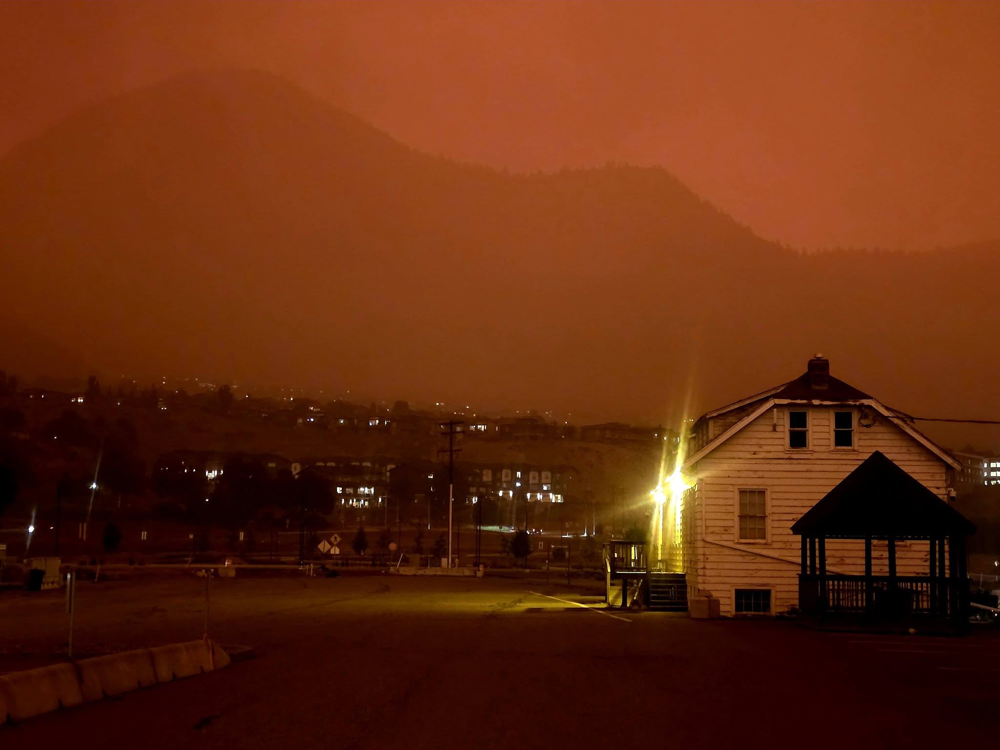 Buildings are seen in the red haze of wildfire smoke.