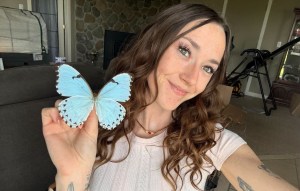A young woman holds up a pair of butterfly wings.