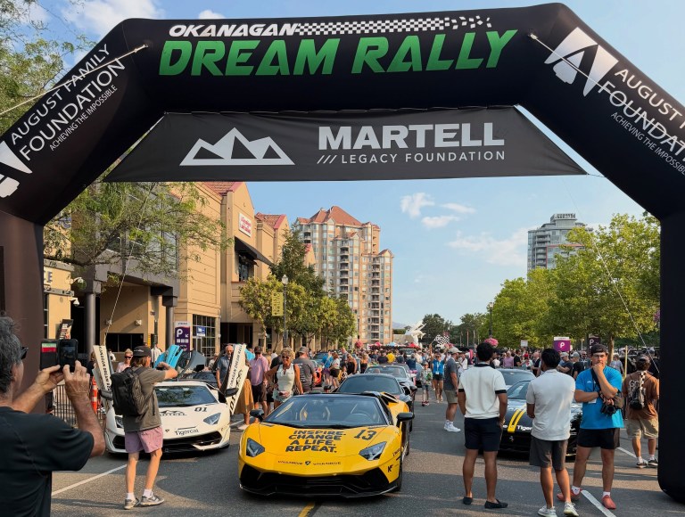 The beginning of a car parade with fancy cars is seen.