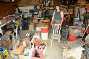 A woman stands in a garage surrounded by boxes of belongings.