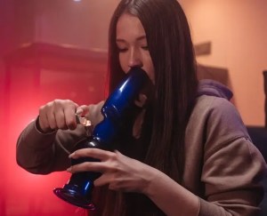A picture of a woman taking a bong hit.