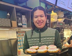 A smiling man holds a tray of decorated bannock.