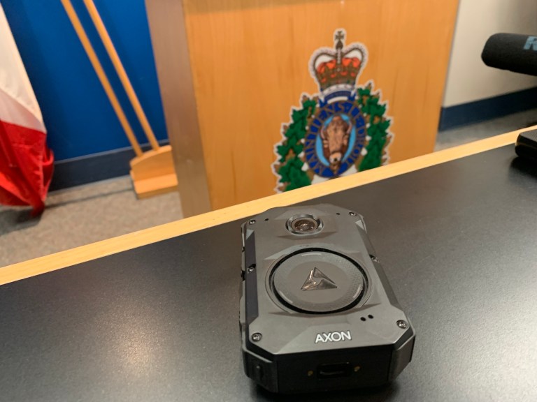 An RCMP body camera on a desk with an RCMP logo in the background.