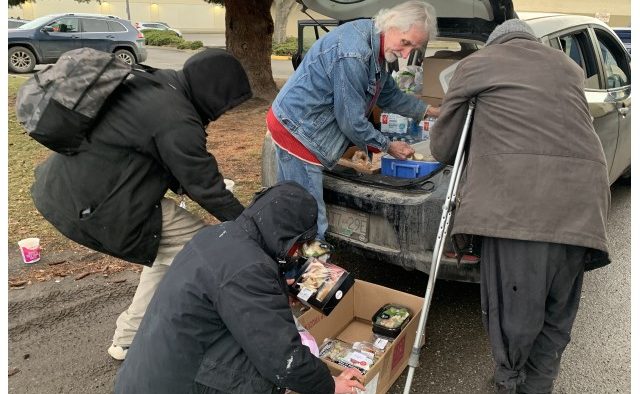 A man delivers food donations from the back of a car.