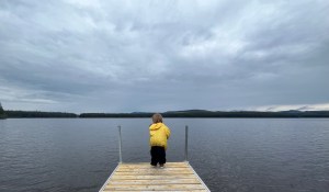 A child on a dock under a cloudy sky.