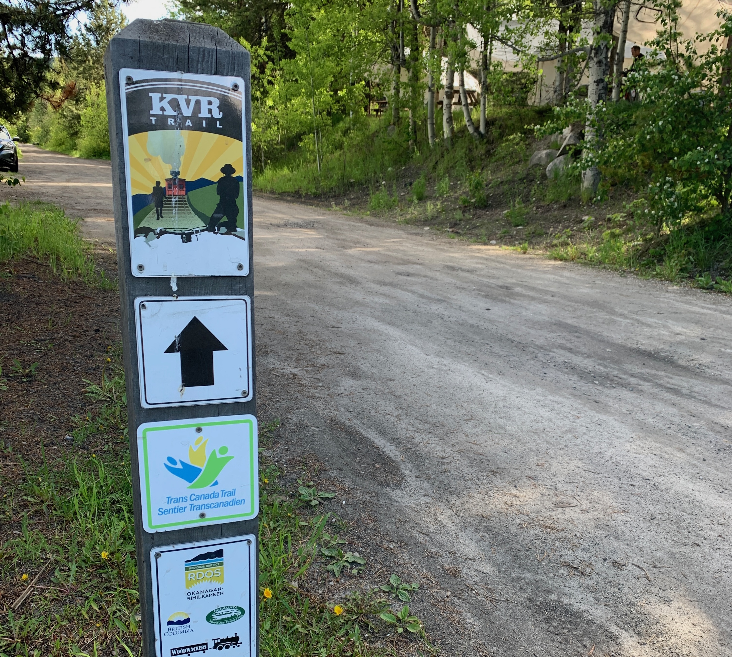 A sign along a trail surrounded by trees.