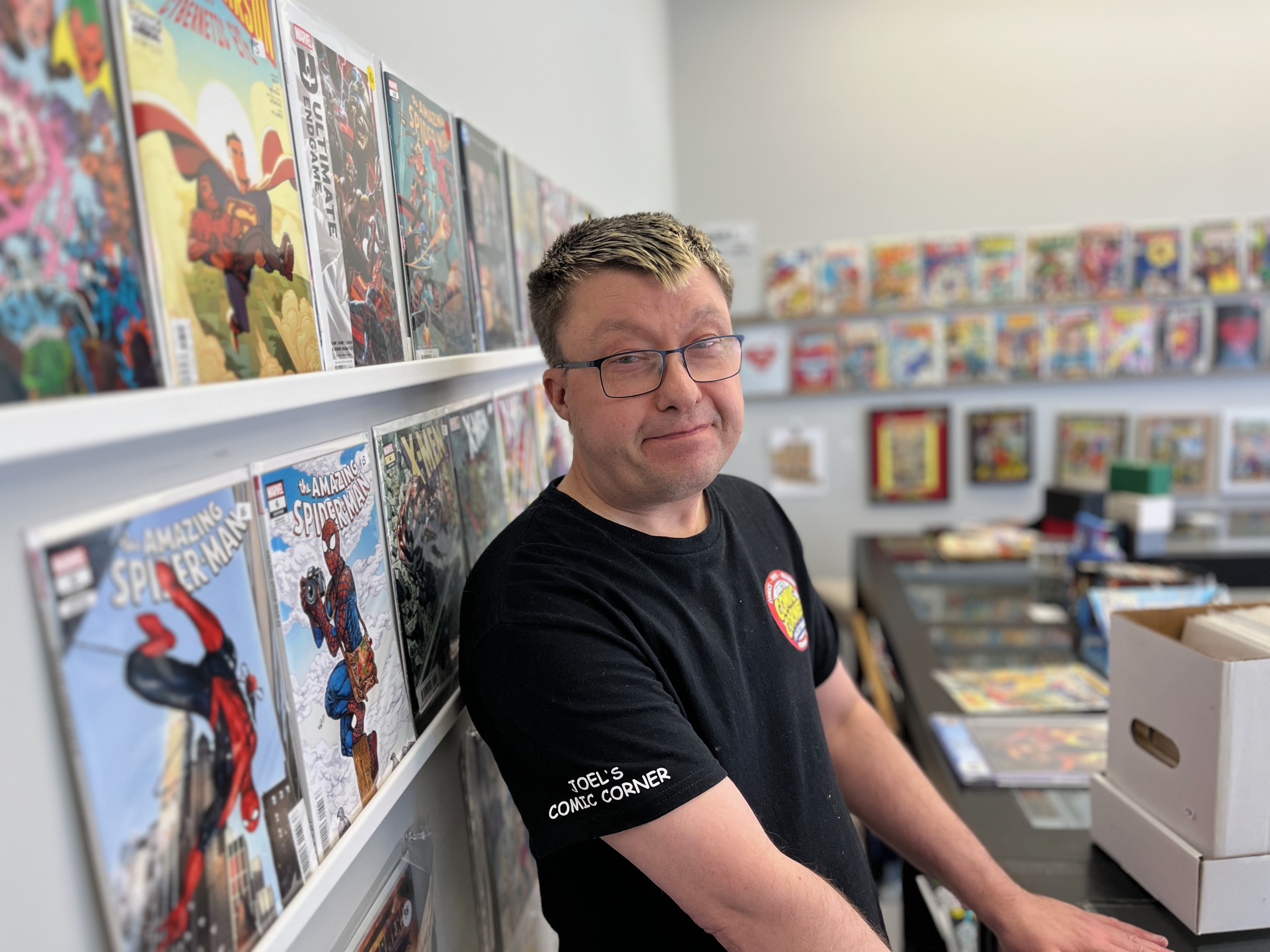Comic books line the walls as a man in a black T-shirt stands in a store.