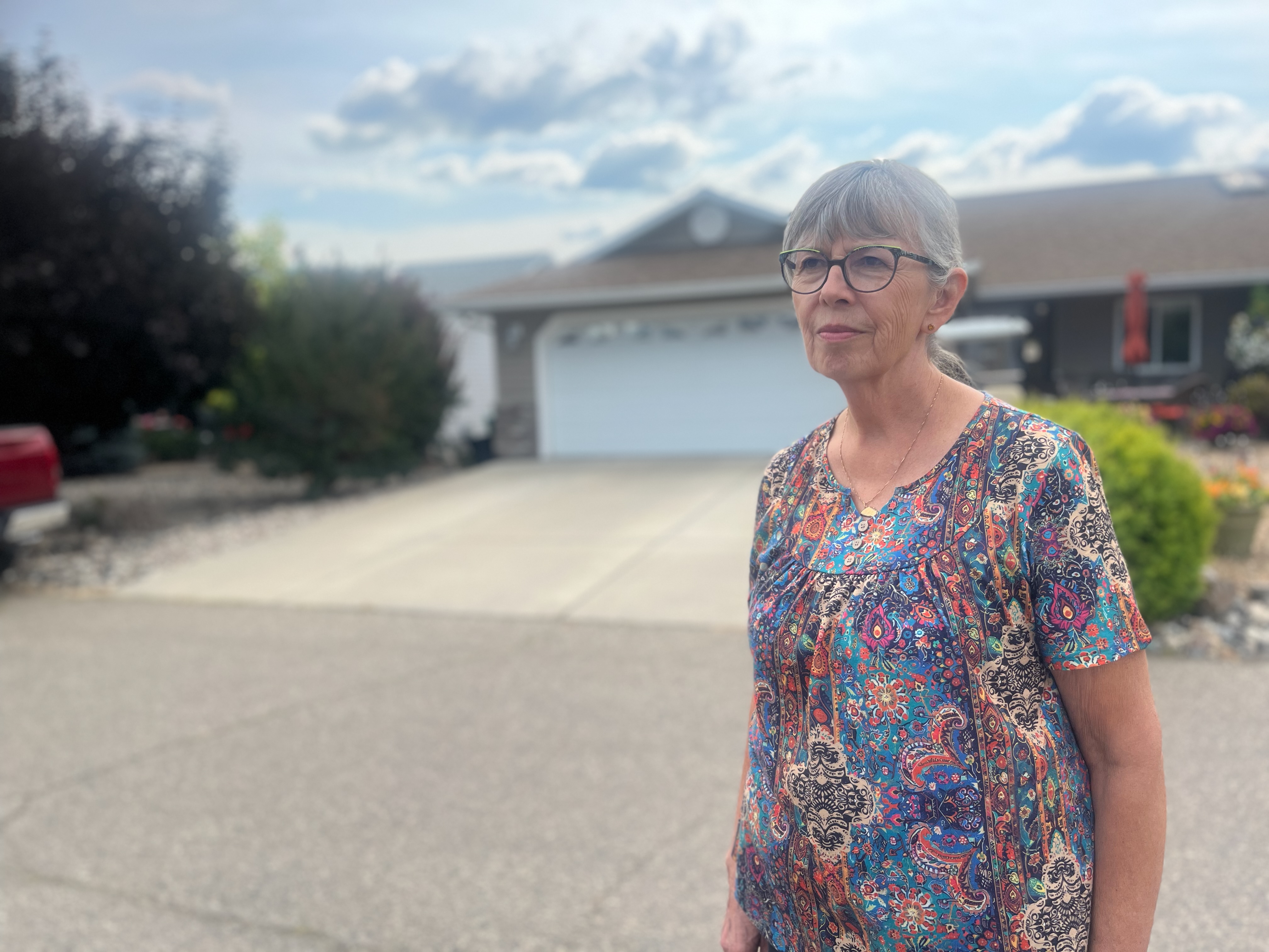 A woman stands outside her home.