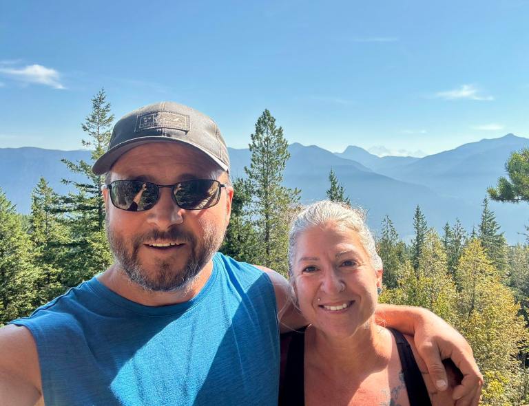 A man and woman with their arms around each other are smiling.