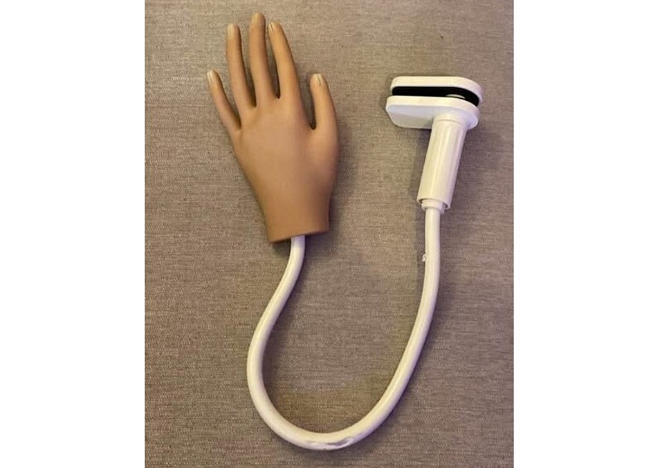 A rubber hand is attached to a cord with a clip on the end.