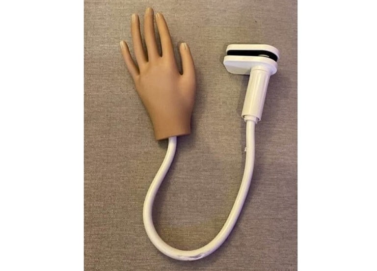 A rubber hand is attached to a cord with a clip on the end.