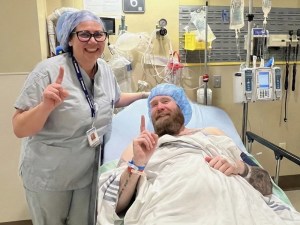 A healthcare worker stands next to a patient's hospital bed.
