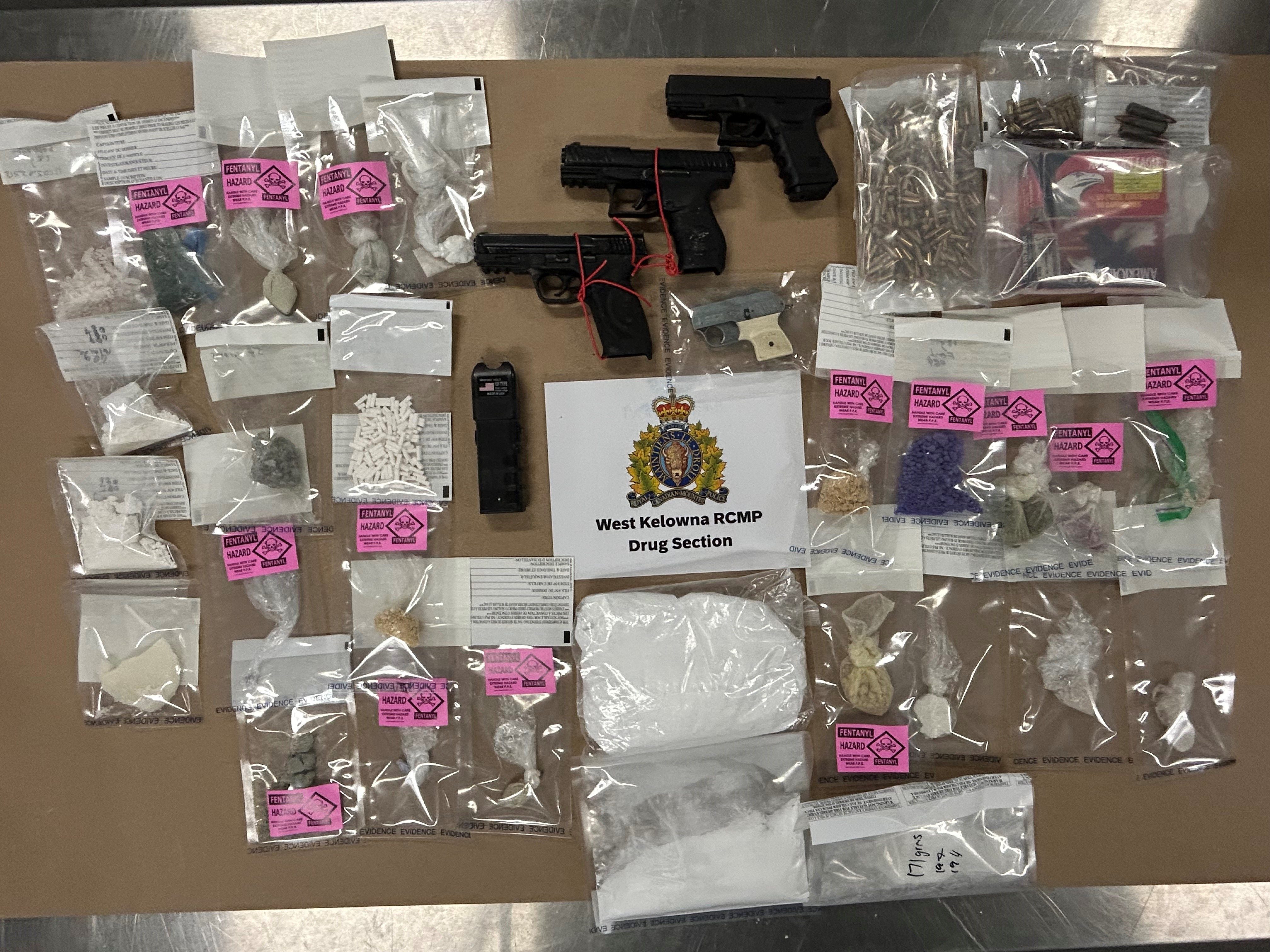 Several types of drugs and handguns laid out on a table with the RCMP logo.