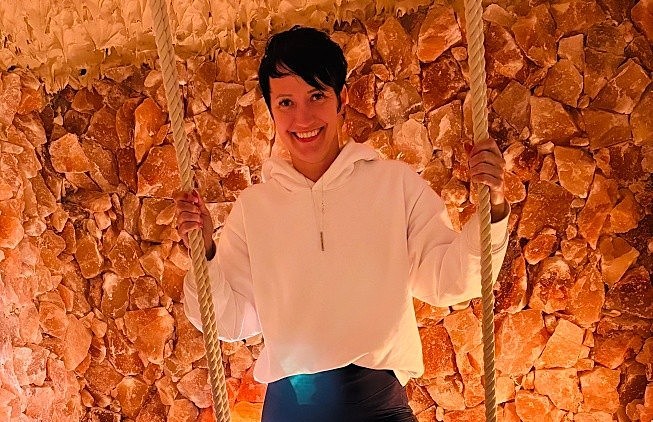 A woman stands in front of a wall with Himalayan rock salt on it.