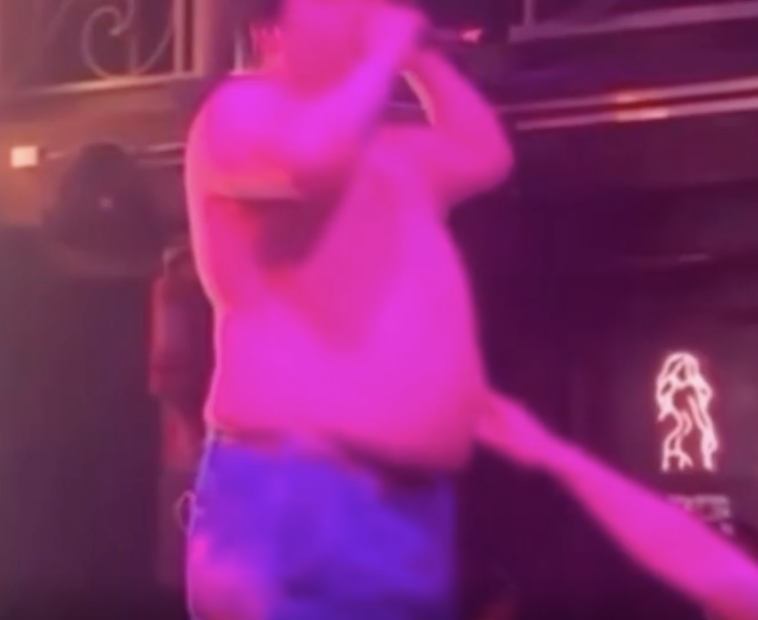 A person sticking their finger in a singer's belly button.