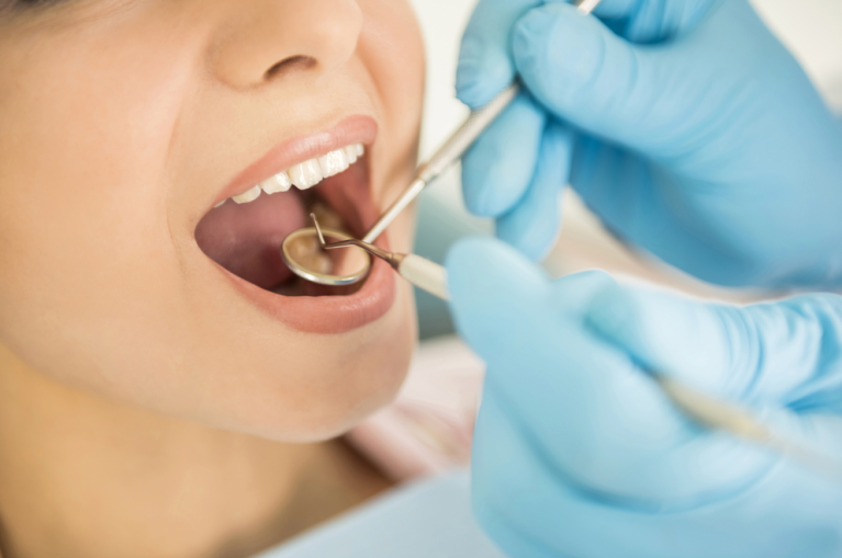 A dentist looks into a patients mouth with a mirror.