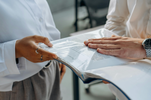 A woman and man in business attire hold a binder.