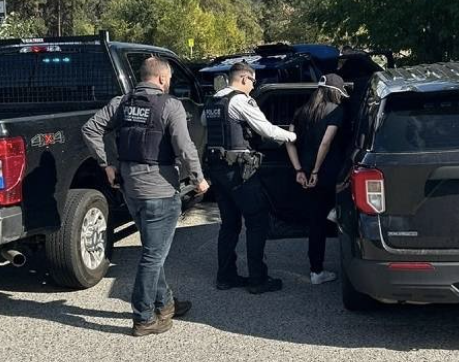 Two police officers putting someone in handcuffs into a vehicle.