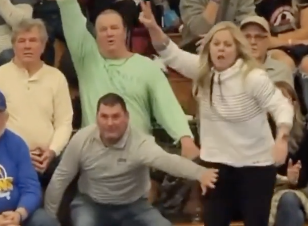 A man stopping a woman from running out into a wrestling tournament.
