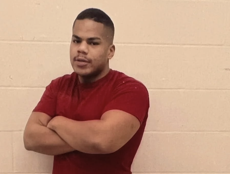 A man wears his prison clothes and folds his arms.