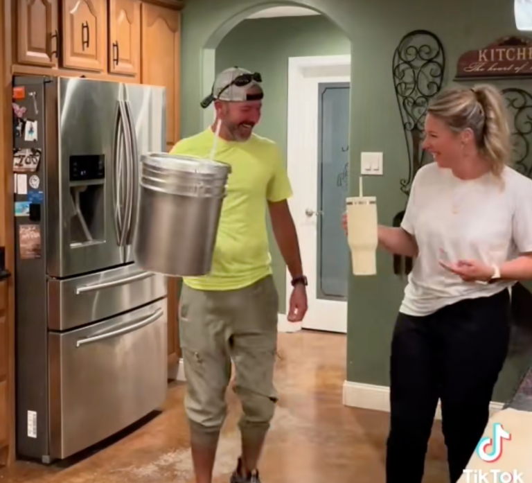 A man holds a homemade huge silver travel mug and a woman holds large travel mug.